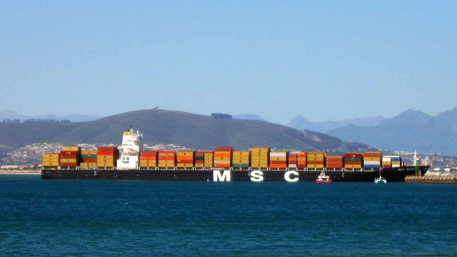MSC container ship stacked with colourful boxes sailing past mountains off Cape Town