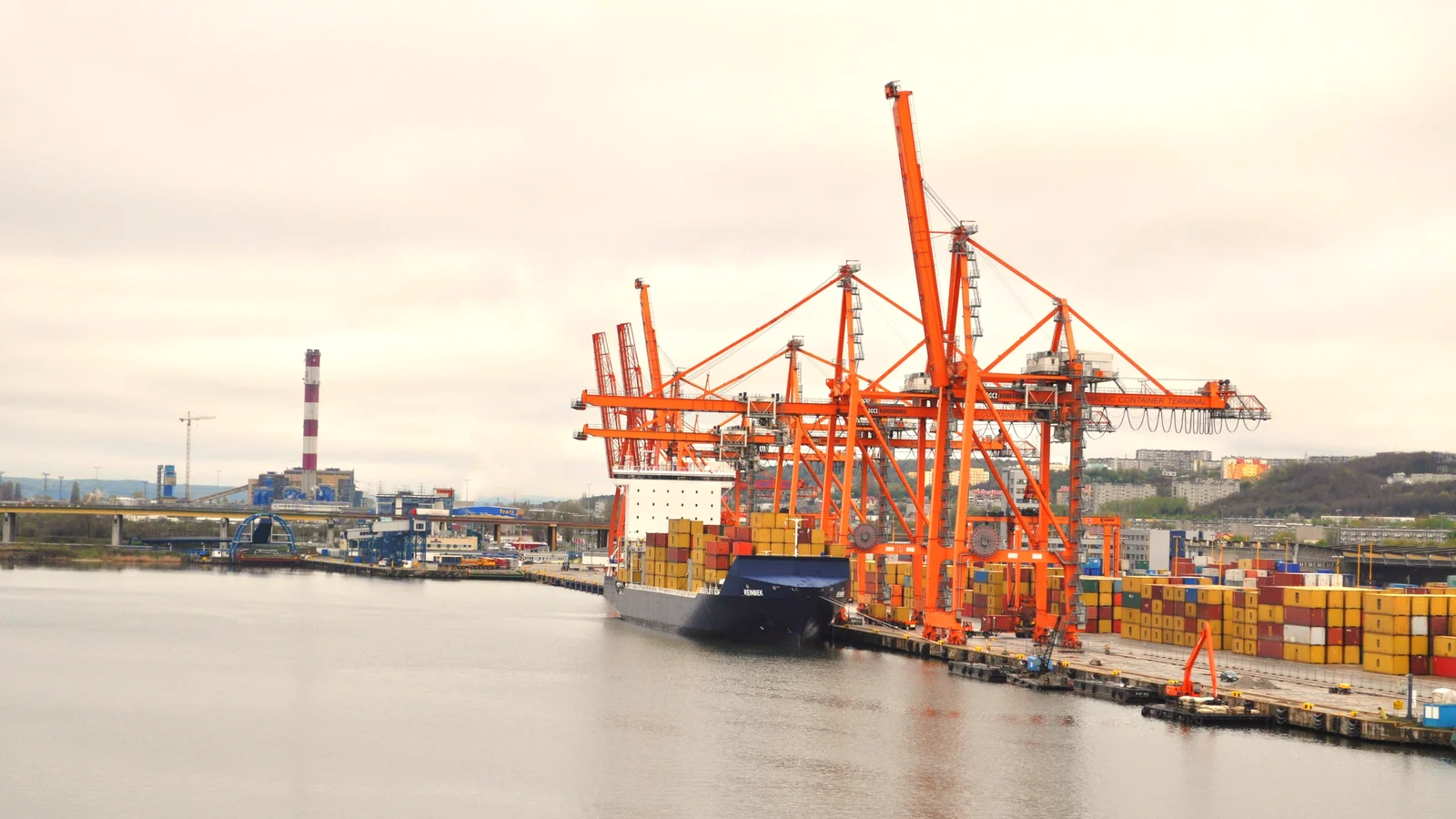 Container ship alongside a quay under orange gantry cranes in Gdynia