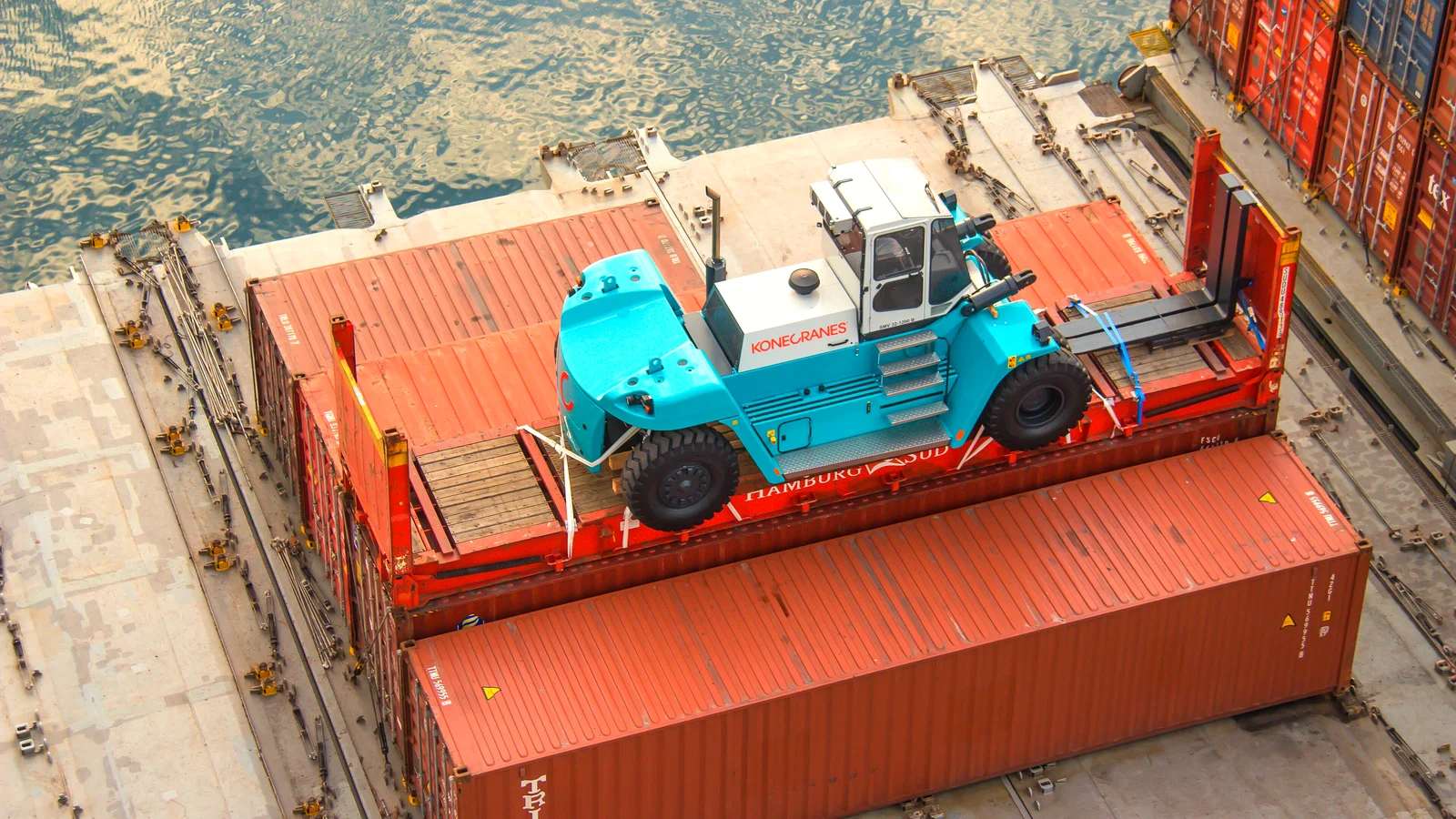 Port machine lashed on red flat rack containers on the deck of a cargo ship in Helsingborg