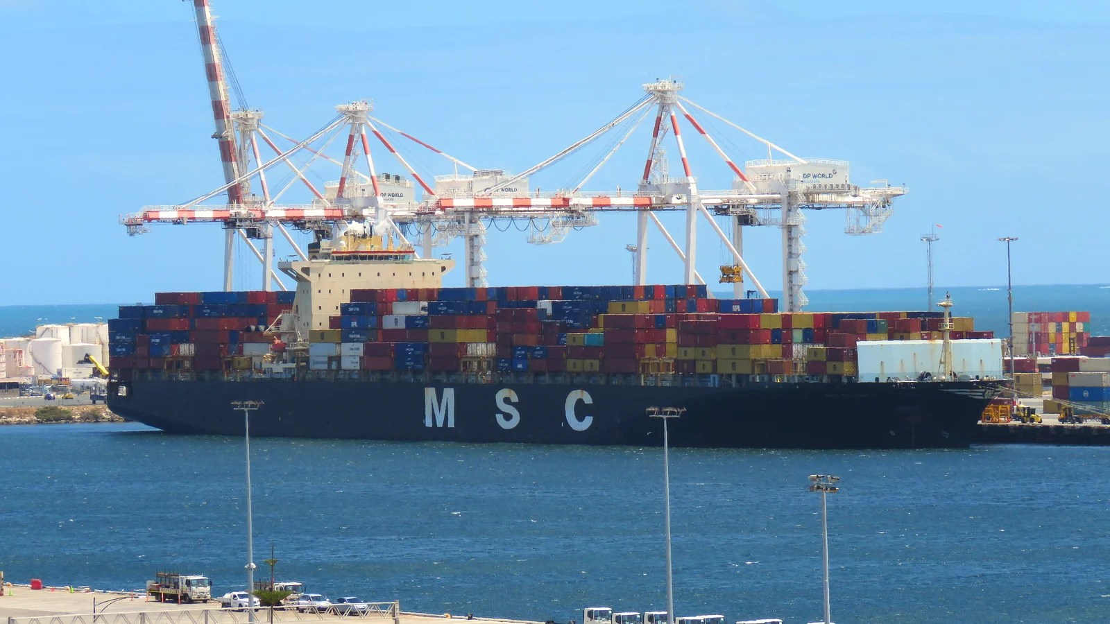 MSC container ship loaded with colourful boxes berthed under gantry cranes on a sunny day